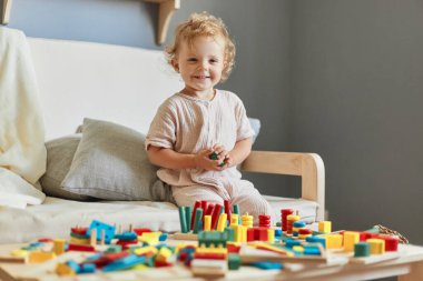 Ahşap inşaat seti. Montessori öğrenme yaklaşımı. Bilişsel gelişim bulmacaları. Mutlu gülümseyen küçük sarışın kız bebek evde tahta ayıklayıcı oyuncaklarla oynuyordu..