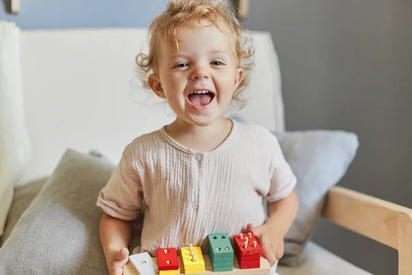 stock image Toddler's imaginative play. Montessori learning tools. Laughing blonde little blonde baby girl palying with wooden sorter toys at home interior