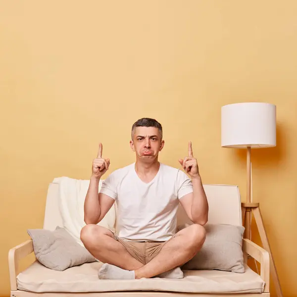 Nešťastný Smutný Muž Bílém Tričku Šortkách Sedící Pohovce Béžovém Pozadí — Stock fotografie