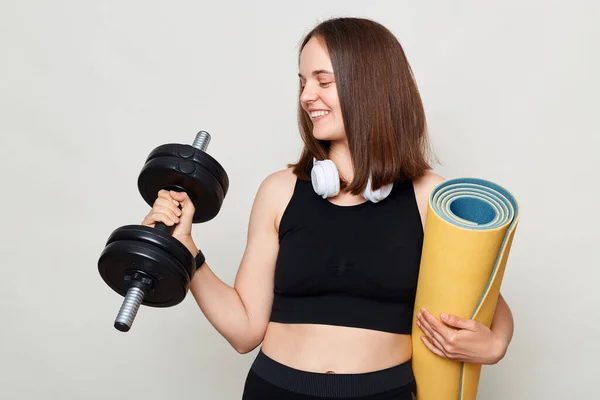 Vrolijke Bruinharige Vrouw Met Opgerolde Fitnessmat Gekleed Actiefwear Geïsoleerd Grijze — Stockfoto