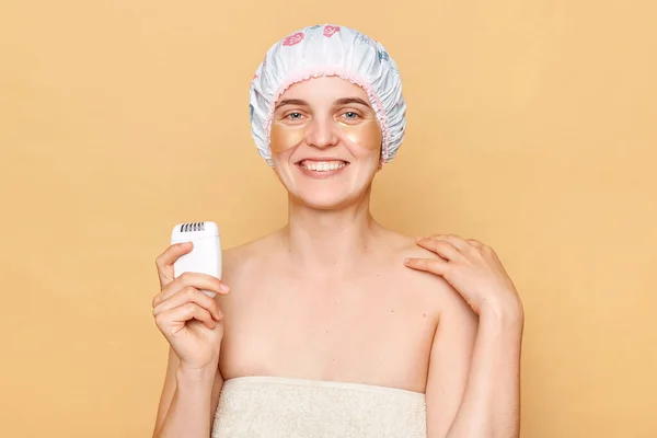 Optymistyczna Kobieta Nosząca Czepek Prysznicowy Stojąca Beżowym Tle Trzymająca Depilator — Zdjęcie stockowe