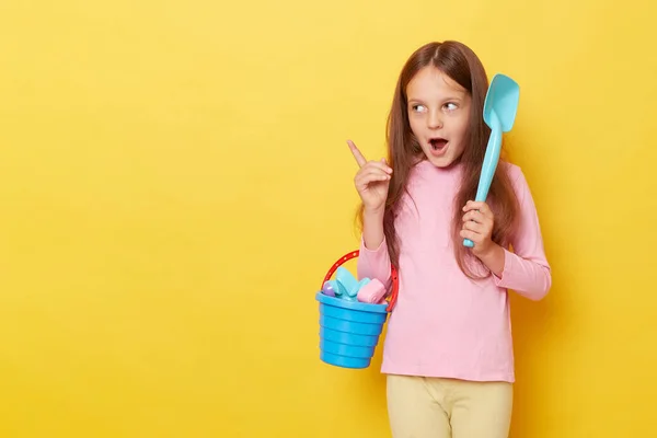Удивлённая Маленькая Девочка Обычной Одежде Игрушками Песочницы Ведром Жёлтом Фоне — стоковое фото