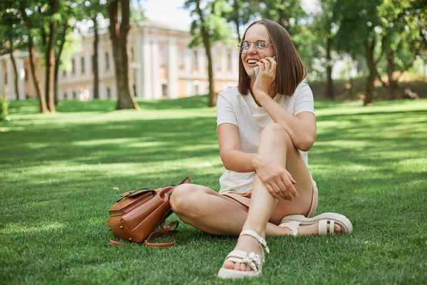 Wanita Ceria Yang Menarik Mengenakan Kaos Putih Duduk Rumput Taman — Stok Foto
