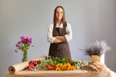 Yaratıcı çiçekli çalışma alanı. Küçük işletme çiçekçisi. Çeşit çeşit çiçek koleksiyonu. Çiçek temalı dekor. Çiçekçide kendine güveni tam bir çiçekçi. Gri arka planda tek başına duruyor.