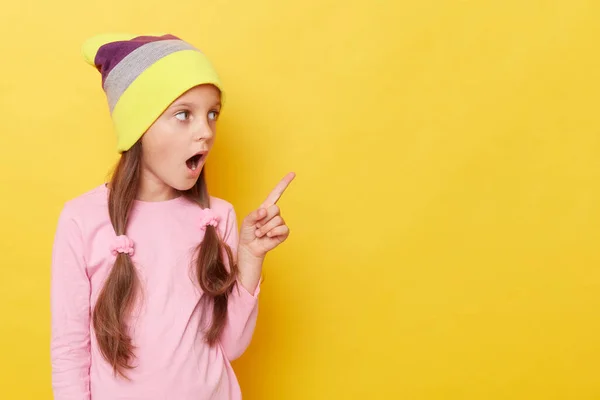 Шокированная Маленькая Девочка Хвостиками Шляпе Шапочки Стоящая Изолированно Желтом Фоне — стоковое фото