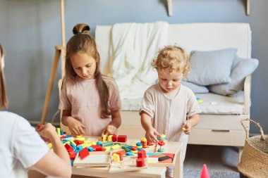 Oyun ve oyuncaklarla çalışıyorum. Akıllıca bir eğitim dersi. Yoğunlaşmış kız kardeşler ahşap eğitici oyuncaklarla birlikte öğreniyorlar. Homer Interior 'da birlikte oynuyorlar..