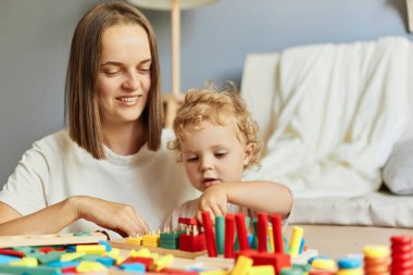 Oyuncak bebek aktiviteleri. Renkli anaokulu oyunları. Yaratıcı gelişim için tahta bloklar. Mutlu anne, küçük kızıyla oynuyor. Ev içinde oyun oynuyor.