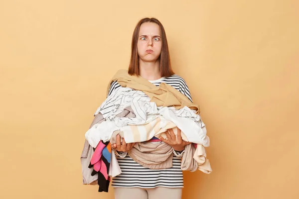 Tired Exhausted Brunette Woman Holding Pile Clothes Hands Isolated Beige — Stock Photo, Image