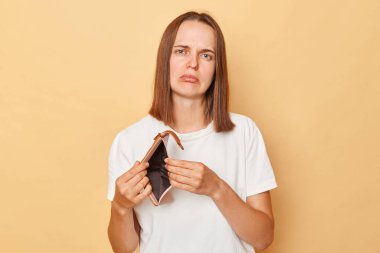 Beyazlı genç bir kadın bej arka planda izole bir cüzdan taşıyor. Ağlıyor ve mutsuz suratlı kameraya bakıyor. Yaşamak için parası yok..