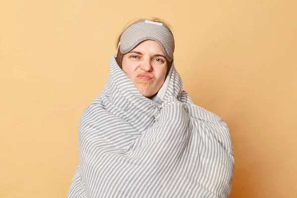 Niezadowolona Nieszczęśliwa Kobieta Owinięta Kocem Ubrana Śpiącą Maskę Beżowym Tle — Zdjęcie stockowe