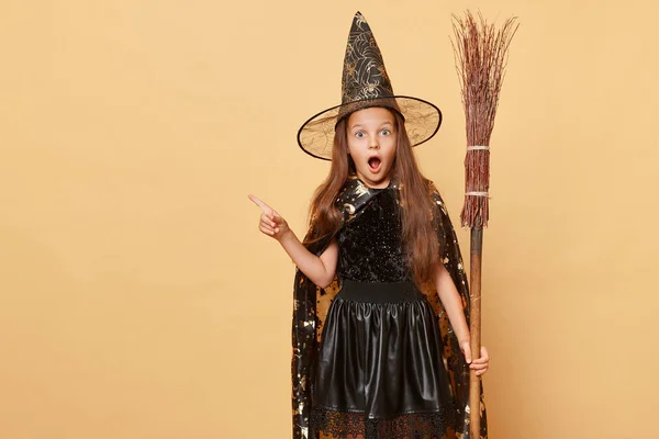 Překvapená Dívka Oblečená Kostýmu Čarodějnice Drží Koště Izolované Přes Béžové — Stock fotografie
