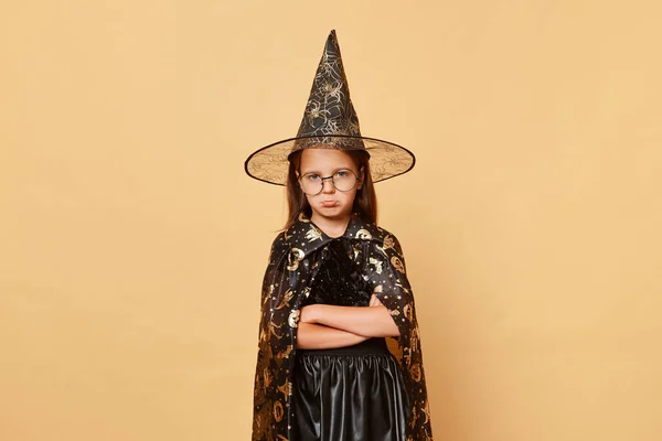 Грустная Оскорбленная Девочка Костюме Ведьмы Черной Шляпе Изолированном Бежевом Фоне — стоковое фото