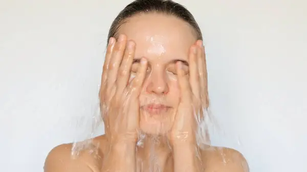 Fresh and clean face. Female facial care. Natural beauty routine. Healthy skincare habits. Hygiene and cleanliness. Young woman washing het face with water isolated over white background.