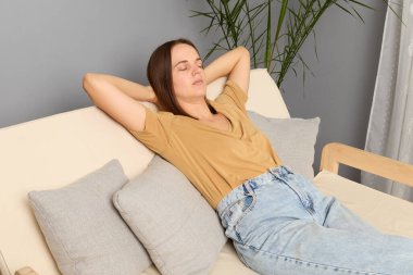 Modern oturma odasındaki koltuğun arkasında oturan gençler, evde rahat bir şekerlemenin tadını çıkarıyorlar, gözleri kapalı, bir rüyada kaybolup, dinleniyorlar..