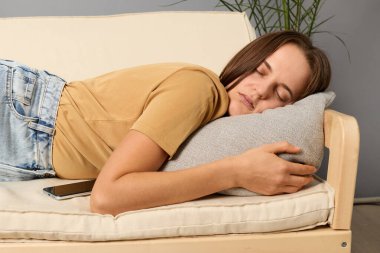 Gündüz rahatlaması. Kanepe uykusu. Yorgunluk nöbeti. Yorgun dinlenme. Uykusuz geceler. Beyaz kadın oturma odasında kanepede uzanıyor ve iç mekanda uyuyor..