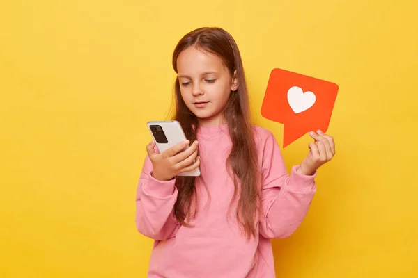 Social media content. Like feedback. User app. Brown haired little girl wearing pink sweatshirt browsing internet watching internet content showing blogger heart icon reading kids blog news.