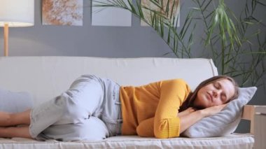 Çekici, sakin, rahat, sarı gömlek ve kot pantolon giyen bir kadın kanepede uzanıyor. Haftasonu uyukluyor, uyukluyor ve boş zamanlarında tatlı rüyalar seyrediyor..