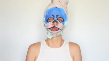 Kadın derisi rutini. Kozmetik maske uygulaması. Sağlık ve cilt bakımı tedavisi. Gençleşme için spa tedavisi. Hayvanın ağızlık maskesiyle duş aldıktan sonra kafasında havlu olan neşeli kız.