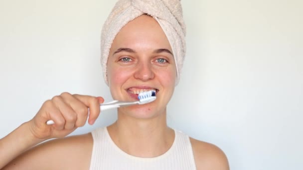 在浴室里做日常的牙病护理 年轻女子裹着毛巾 用塑料牙刷刷牙 关心家里的牙齿卫生 — 图库视频影像