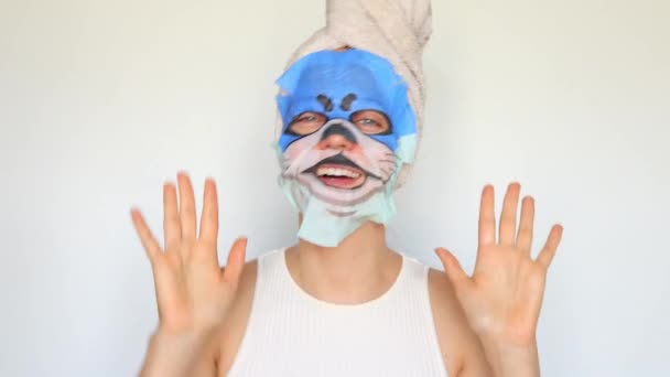 フェイスケアと美容トリートメント 動物のマズルの顔のマスクでシャワーを浴びた後 頭にタオルをかけた若い少女は白い背景で隔離された手順を保湿します — ストック動画