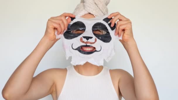 フェイシャルマスクを加水する 皮膚の健康のためのコラーゲン 皮膚の若返りプロシージャ アンチエイジングスキンケア パンダのマスクでシャワーを浴びた後 彼女の頭にタオルが付いている楽しい少女 — ストック動画