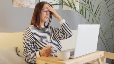 Üzücü, kahverengi saçlı, günlük giysiler giyen, gözlüklü, evde çalışan, grip belirtileri gösteren, internet projesinin düzgün çalışması gereken bir kadın..