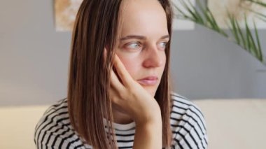 Gergin kafa karışıklığı. Dehşet verici panik. Korkmuş ve endişeli, siyah saçlı, çizgili tişörtlü bir kadın. Evde oturuyor. Stresli ve depresif düşünme sorunları yaşıyor..