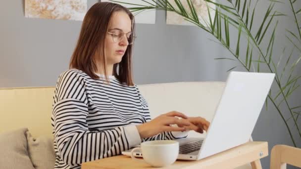 网络空间连接 在线职业 生病的棕色头发女人穿着休闲装 戴着眼镜 在家里做室内按摩 为头疼的太阳穴按摩 — 图库视频影像