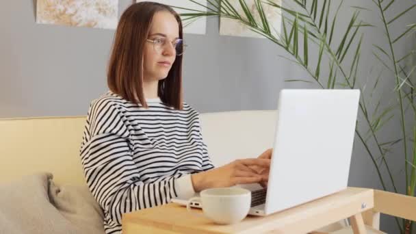 网上交易 在家工作 网络空间学习 惊慌失措的棕色头发女人穿着休闲装 戴着眼镜在家里上网打字 容易出错 — 图库视频影像