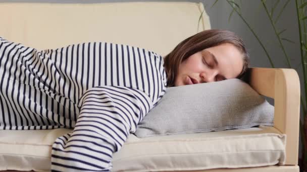睡眠中の女性は 疲れているストライプのシャツを着てソファーで昼寝し 眠れない夜の後に眠ろうとしている毎日目を閉じて疲れ果てた — ストック動画