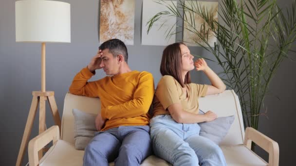 自宅でソファーに座りながら喧嘩をしている美しい若いカップルは 心理的なセッションを持つお互いから離れて 神経質で不幸な家族の問題の誤解に見えます — ストック動画