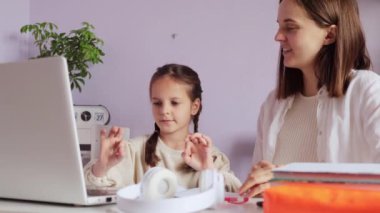 Saçları örgülü güzel bir kız. Annesiyle birlikte dizüstü bilgisayarın önünde oturuyor. Ödev yapan öğrencilere parmak jimnastiği yapıyor..