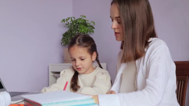 娘の研究 学生生活 家族の繋がり 母親と宿題をするホームインテリアで母親の助けを借りて学校の仕事をしているデリケートな少女 — ストック動画
