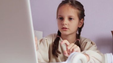 Basit bir e-öğrenme, çevrimiçi kurslar aracılığıyla, atkuyruklu beyaz gömlekli bir kız, masasında dizüstü bilgisayar başında oturuyor, online matematik dersine katılıyor, parmaklarını saymak için kullanıyor..