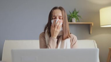 Hasta, kahverengi saçlı bir kadın dizüstü bilgisayarının önünde oturmuş grip belirtileri göstererek öksürüyor. Genç bir kadın serbest çalışıyor..