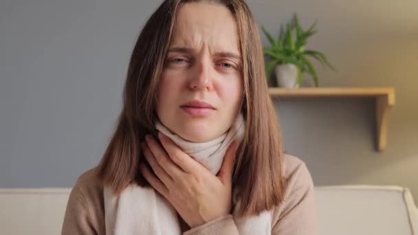 スカーフで包まれた茶色の髪の病気の女性は 痛みのグリップウイルスに苦しみ 家庭内インテリアのソファに座って咳 — ストック動画