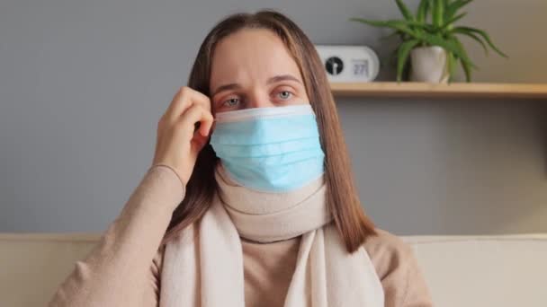 科罗纳威斯病疾病感染 流感药物 年轻的棕色女人坐在沙发上 戴着口罩 感觉身体不健康 有感冒 打喷嚏 流鼻涕的症状 — 图库视频影像