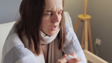 Sağlık tedavisi. Coronavirüs salgını. Hastalık enfeksiyonu. Sağlıksız ilaç. Ekoseye sarılı hasta kadın evdeki kanepede oturuyor..