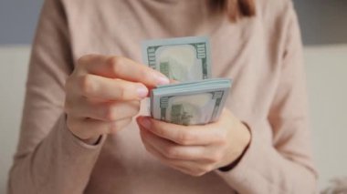 Tanınmayan bir iş kadınının elleri Amerikan parasını tutuyor. Kadın kasiyer Amerikan dolarlarını dikkatlice sayıyor. Elinde dolar banknotları tutan zengin kadın..