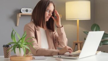 Uzaktan kumanda. Yorgun ve serbest çalışan. Ev işyerinde uzaktan bilgisayar kullanan yorgun bir kadın gözlerini ovuştururken yorgun düşmüş..