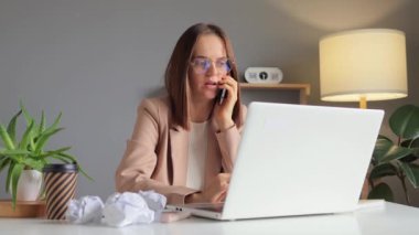 Şirket iletişimi. Modern ofiste iş ortağıyla iş sorunları hakkında konuşurken cep telefonuyla konuşan meşgul bir iş kadını..