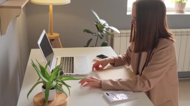 専門の女性教師リモートチューターは テーブルで職場に座って自宅のオフィスで働くウェブカムビデオ会議バーチャルミーティングによってオンラインクラスを与えます — ストック動画