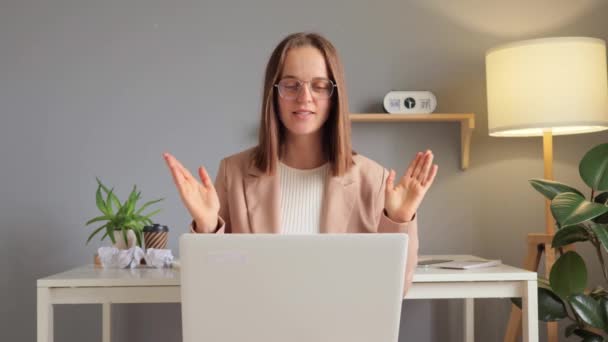オフィスの職場でラップトップでオンラインで働く陽気な茶色の髪の女性は 学生と話したり コンピュータ上の同僚と会ったりするビデオ通話インターネットウェビナーを持っています — ストック動画