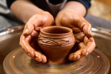 Çömlek çarkı. Esnaf 'ın eseri. Kirli form. El işi yeteneği. Çamur çalışıyor. Potter 'ın elleri nazikçe ve kesinlikle çömlekçinin tekerleğindeki kil tencereyle şekillendi..