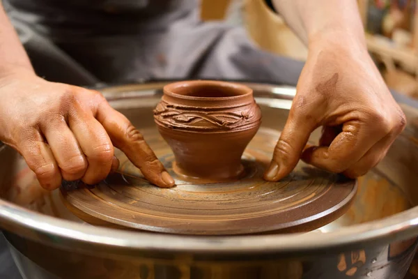 Culture and hobby. Shaped vase. Handcrafting circle. Concentrated ceramist. Potter\'s hands gently and surely formed by clay pot on potter\'s wheel.