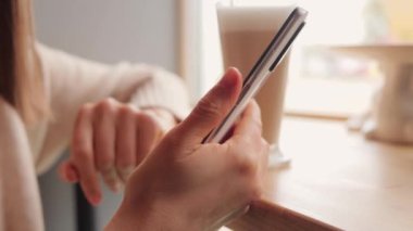 Tanımlanamayan kadının elleri akıllı telefonu tutarken pencere kenarında oturup internet sayfalarını karıştırıyor internet haberleri okuyor ya da online alışveriş yapıyor..