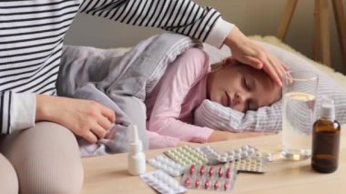 Küçük kızın ateşi var. Yatakta yatıyor. Annesi özen gösteriyor ve hasta kızını battaniyeyle örten vücudunun sıcaklığını hissediyor..