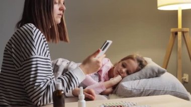 Siyah saçlı bir kadın internette doktorla kızının ateşinin çocuk alnına değdiğini vücut ısısını ölçüp grip tedavisini sorduğunu konuşuyor..