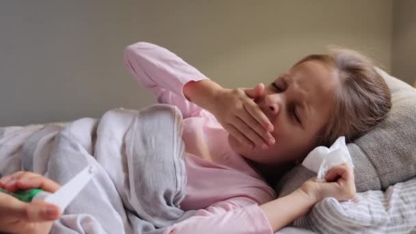 生病的棕色头发小女孩躺在床上 盖着毯子 打呵欠 感到困倦 满嘴都是手掌 有流感症状 请病假时在家休息 — 图库视频影像