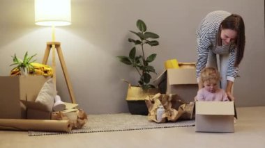 Kafkasyalı anne ve kız çocuğu boş bir karton kutuya bindirip taşınmak için yeni bir daireye yerleştiriyorlar..